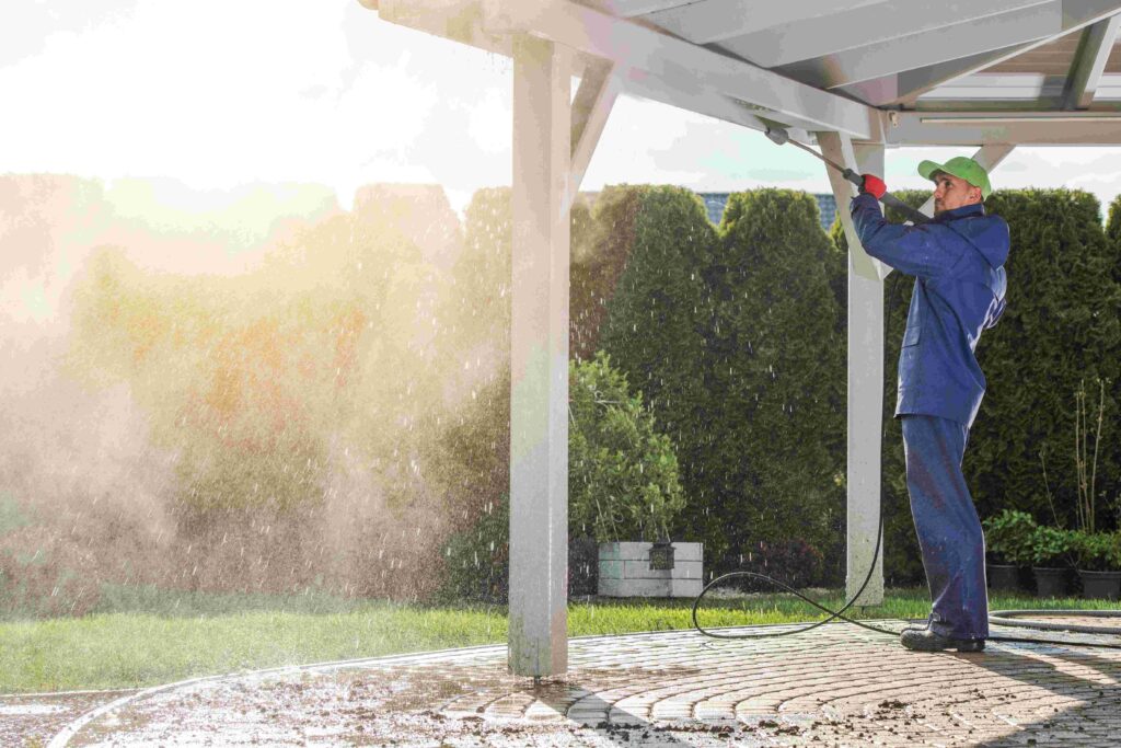 Worker with a pressure washer cleaning the roof of a Patio House